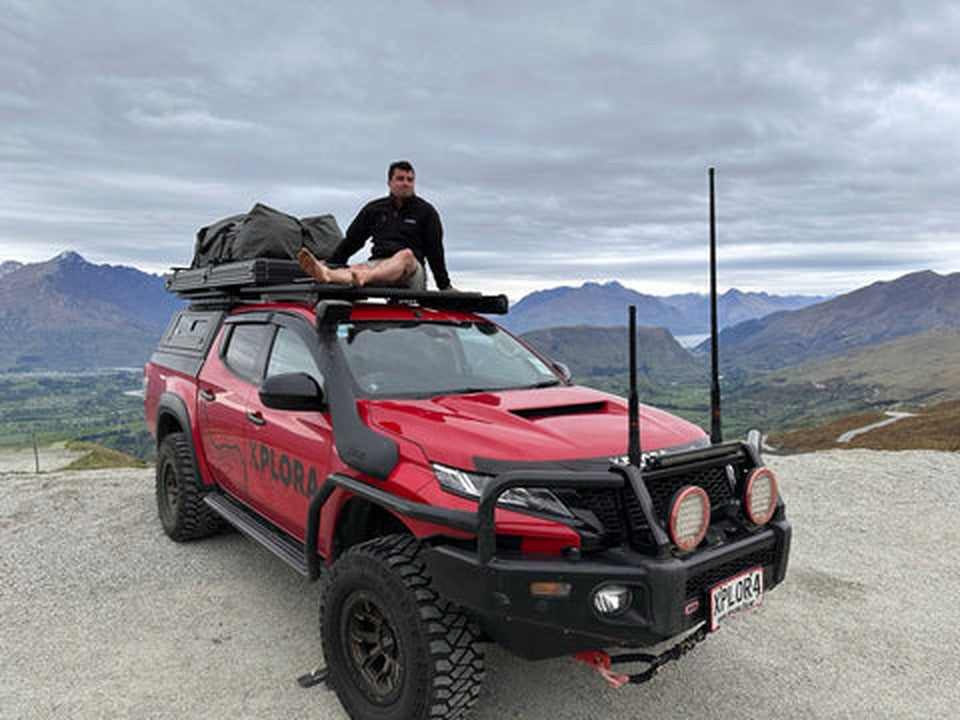 Blake O'Loughlin with the red Xplora four wheel drive in the mountains